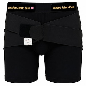 Op de afbeelding: Een zwart compressiekledingstuk met een brede tailleband met de tekst London Joints Care en een kleine Britse vlag. Het kledingstuk heeft verstelbare wikkelbanden met klittenbandsluitingen en een wit label met de tekst LJC.