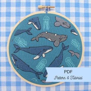 May include: Embroidered hoop art featuring a blue whale, gray whale, and jellyfish on a teal background. The hoop is made of wood and has a brass screw. The text "PDF Pattern & Tutorial" is visible at the bottom of the image.