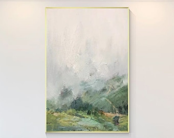 May include: A large abstract landscape painting with a gold frame. The painting features a misty green and white landscape with a hint of orange. The painting is hanging above a fireplace in a modern living room.