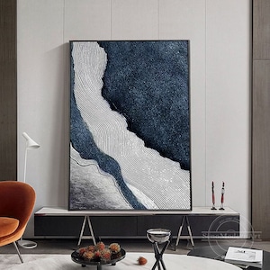 Pu&ograve; includere: Un'opera d'arte murale rettangolare con una composizione astratta testurizzata. L'opera presenta sezioni blu navy profondo con una superficie granulare contrastate da un'area chiara caratterizzata da sottili linee ondulate parallele.