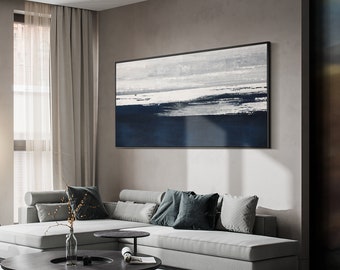 May include: A white sectional sofa with gray and blue throw pillows sits in a modern living room. A large abstract painting with blue and white brushstrokes hangs on the wall above the sofa. A black coffee table sits in front of the sofa.