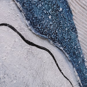 Pu&ograve; includere: Un dipinto astratto materico caratterizzato da uno spesso strato di vernice blu scuro dalla superficie granulosa, in contrasto con un'area grigio chiaro liscia con striature orizzontali e una sottile linea ondulata nera dipinta a mano.