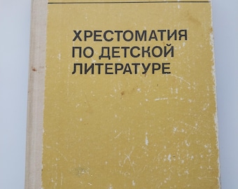 Puede incluir: Un libro antiguo con una cubierta amarilla y lomo blanco. La cubierta presenta texto negro en escritura cirílica, incluido el título "Хрестоматия по детской литературе." El libro es un libro de texto para escuelas pedagógicas.