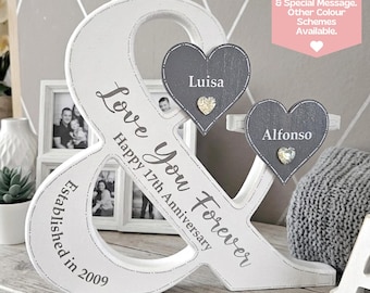 May include: A white wooden ampersand sign featuring the text Love You Forever, Happy 17th Anniversary, and Established in 2009. Two grey wooden hearts are attached, displaying the names Luisa and Alfonzo with small decorative crystal accents.