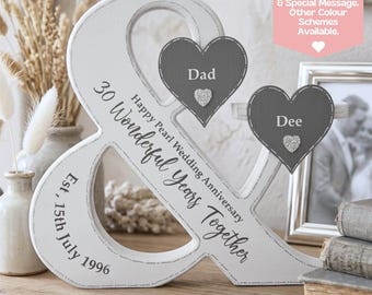 May include: A white wooden ampersand-shaped anniversary decoration. It features the text "30 Wonderful Years Together" and "Happy Pearl Wedding Anniversary." Two gray heart-shaped plaques are attached, each with a name and a glitter heart. The date "Est. 15th July 1996" is also included.