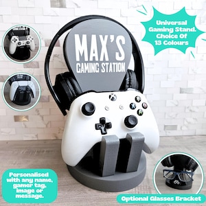 Pode incluir: Um suporte de jogo cinza com um controle Xbox branco, fones de ouvido pretos e o texto "MAX'S GAMING STATION". O suporte tem um suporte para óculos opcional e é personalizado com um nome ou mensagem.