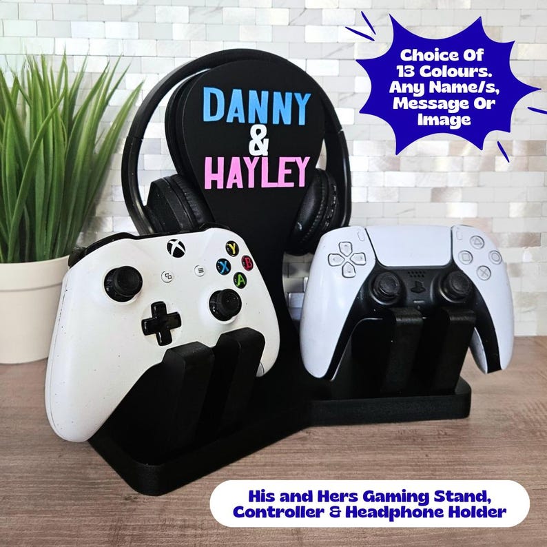 May include: Black gaming stand with white controllers and a headphone holder. The stand features the names "Danny & Hayley" in blue and pink. Text on the stand says "Choice Of 13 Colours. Any Name/s, Message Or Image."