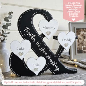 May include: A black ampersand-shaped wooden sign featuring white heart-shaped plaques with the names Mummy, Daddy, Juke, and Evie. The sign includes the text Together, We Have Everything and small decorative crystal hearts on each plaque.