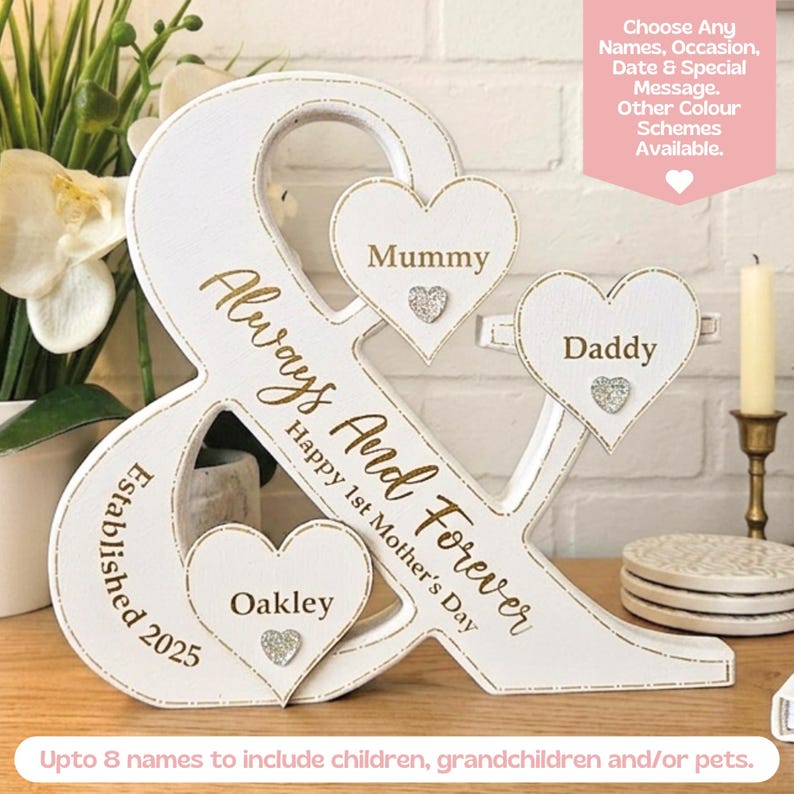May include: A white ampersand-shaped wooden sign featuring gold text that reads Always And Forever, Happy 1st Mother's Day, and Established 2025. Three white heart-shaped plaques are attached, labelled Mummy, Daddy, and Oakley, with small silver glitter hearts.