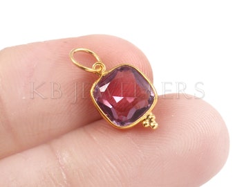 May include: A gold pendant with a square-shaped amethyst gemstone. The pendant has a small loop at the top for attaching to a chain.