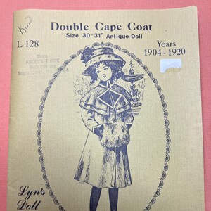 May include: A vintage pattern for a double cape coat for an antique doll, sizes 30-31 inches, from 1904-1920. The cover features a detailed illustration of a doll wearing the coat, with text reading "Lyn's Doll House Patterns."