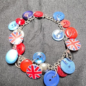 May include: A button bracelet featuring a variety of colorful buttons in red, white, and blue. Some buttons have the Union Jack flag design. The bracelet is connected by a silver chain.