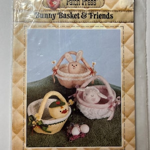 May include: A package featuring a sewing pattern for three Easter-themed baskets: a bunny, a duck, and a lamb. The baskets are shown in a finished state, with pastel colors and decorative elements. The package is labeled "Bunny Basket & Friends."