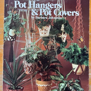 May include: A vintage book cover titled "Crocheted Pot Hangers & Pot Covers" by Barbara Johnston. The cover features various crocheted plant hangers and pot covers, showcasing different designs and colors. The image includes plants in the hangers and covers, with butterflies.