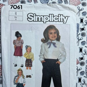May include: Simplicity sewing pattern number 7061 for girls' clothing sizes 4. The pattern includes instructions for making a white blouse with a bow tie, a pair of black pants, and a plaid skirt.