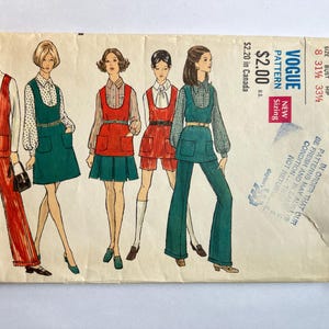 May include: Vintage Vogue pattern envelope featuring illustrations of women in 1970s outfits. The designs include jumpsuits, dresses, and shorts in shades of red, green, and white. The envelope has text indicating the pattern size and price.