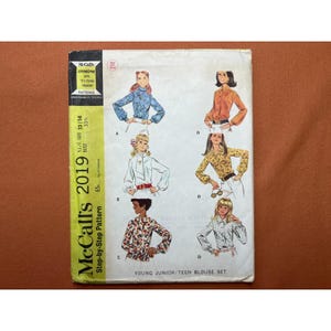 May include: Vintage McCall's 2019 sewing pattern for a young junior/teen blouse set. The pattern features multiple blouse designs with long sleeves and various collar styles. The cover has illustrations of the blouses and text that reads "Step-by-Step Pattern".