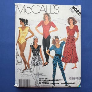 May include: McCall's sewing pattern featuring illustrations of women's clothing designs. The pattern includes a variety of styles, such as a bodysuit, skirt, and leggings. The text on the pattern reads "Focus on Overlock Sewing."