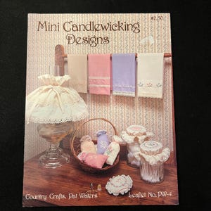 May include: A book cover titled "Mini Candlewicking Designs" features a display of miniature embroidered towels in pastel colors, a lamp, a basket with small sachets, and jars with decorative lids. The cover includes the text "Country Crafts, Pat Waters" and "Leaflet No. PW-4".