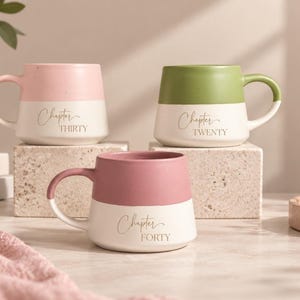 May include: Three ceramic mugs with a two-tone design. Each mug features a coloured top half and a white bottom half. The text "Chapter THIRTY," "Chapter TWENTY," and "Chapter FORTY" is printed in a script and serif font on the white section of each mug.