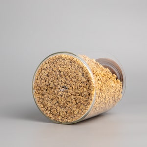 May include: A glass jar filled with golden brown granola. The jar is tilted on its side, revealing the contents.