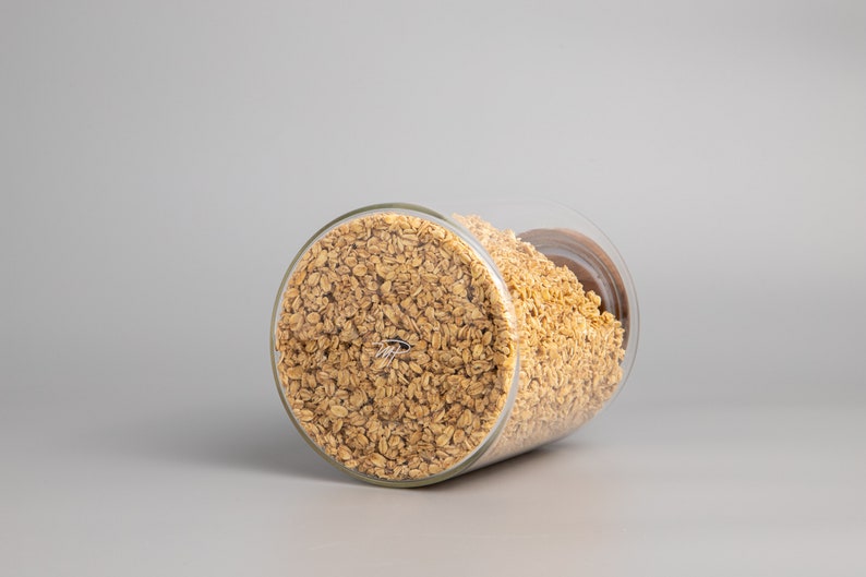 May include: A glass jar filled with golden brown granola. The jar is tilted on its side, revealing the contents.