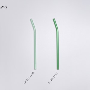 Pu&ograve; includere: Due cannucce piegate sono mostrate verticalmente. Una cannuccia &egrave; color giada chiaro e l'altra &egrave; color giada scuro. Il testo BENT STRAWS appare in alto a sinistra, mentre le etichette LIGHT JADE e DARK JADE sono poste sotto ogni cannuccia.