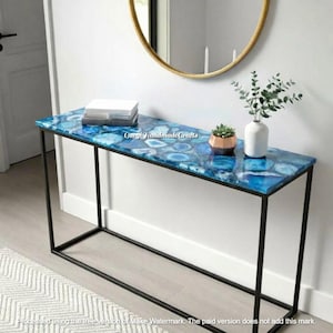 May include: A rectangular console table with a blue agate stone top and a black metal frame. The table is decorated with books, a small succulent in a copper pot, and a white vase with greenery. The text "Cargi Handmade Crafts" is visible on the table.