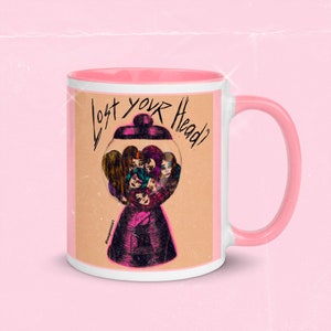 Puede incluir: Taza de cerámica blanca con borde y asa de color rosa. La taza presenta un gráfico de una máquina de chicles con múltiples caras dentro. El texto "Lost your Head?" está escrito en negro en la parte delantera de la taza.