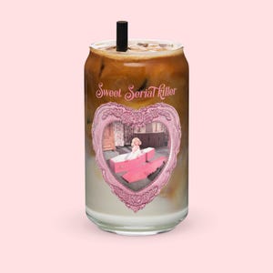 Peut inclure: Une canette de boisson en verre remplie d'une boisson en couches, avec une paille noire. La canette porte une étiquette rose en forme de cœur avec une image vintage et le texte "Sweet Serial Killer".