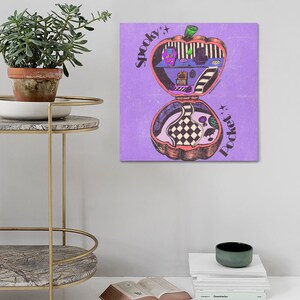 May include: A purple background with a cartoon illustration of a pumpkin shaped pocket-sized house with the words "Spooky Pocket" written on it.