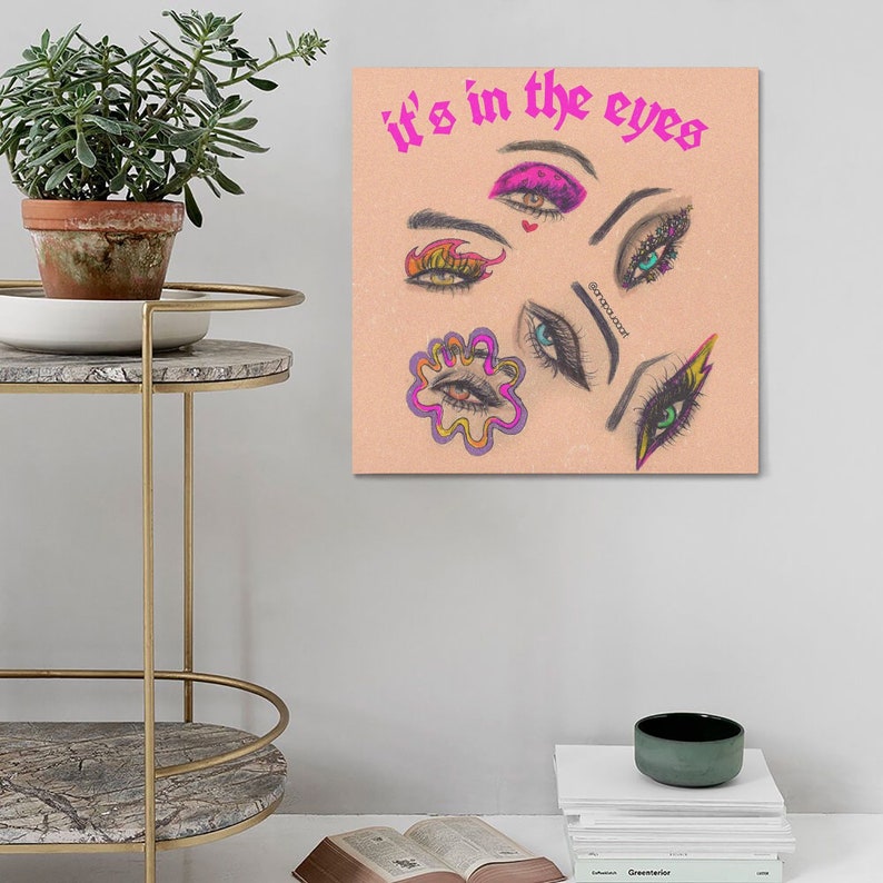 May include: A pink and white illustration of various eyes with different makeup looks. The text "it's in the eyes" is written in pink at the top of the image.