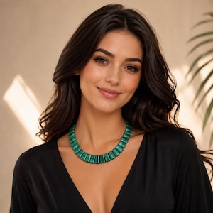 May include: A necklace featuring a series of green and black banded malachite segments arranged in a curved, collar-style design. The individual stone pieces are rectangular with slightly tapered edges, creating a uniform, textured appearance.