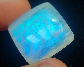 May include: A square-shaped, translucent, white moonstone cabochon with a blue iridescent sheen.