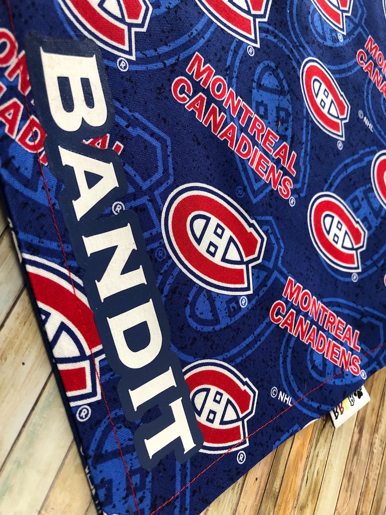 May include: A blue fabric with a pattern of the Montreal Canadiens logo and text. The text "MONTREAL CANADIENS" is in red and white. The word "BANDIT" is printed vertically in white. The fabric has a stitched red border.
