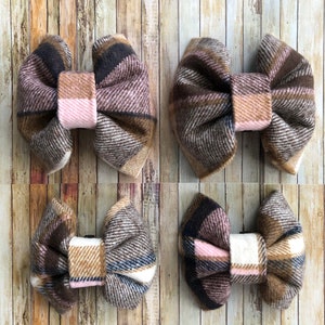 May include: Four plaid fabric hair bows in brown, pink, and white. The bows are arranged in two rows of two.