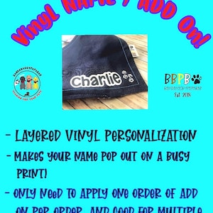 May include: A navy blue pet bandana with the name "Charlie" in white vinyl lettering. The bandana has paw print accents and text that reads "Vinyl Name I Add On!" and "Layered Vinyl Personalisation".