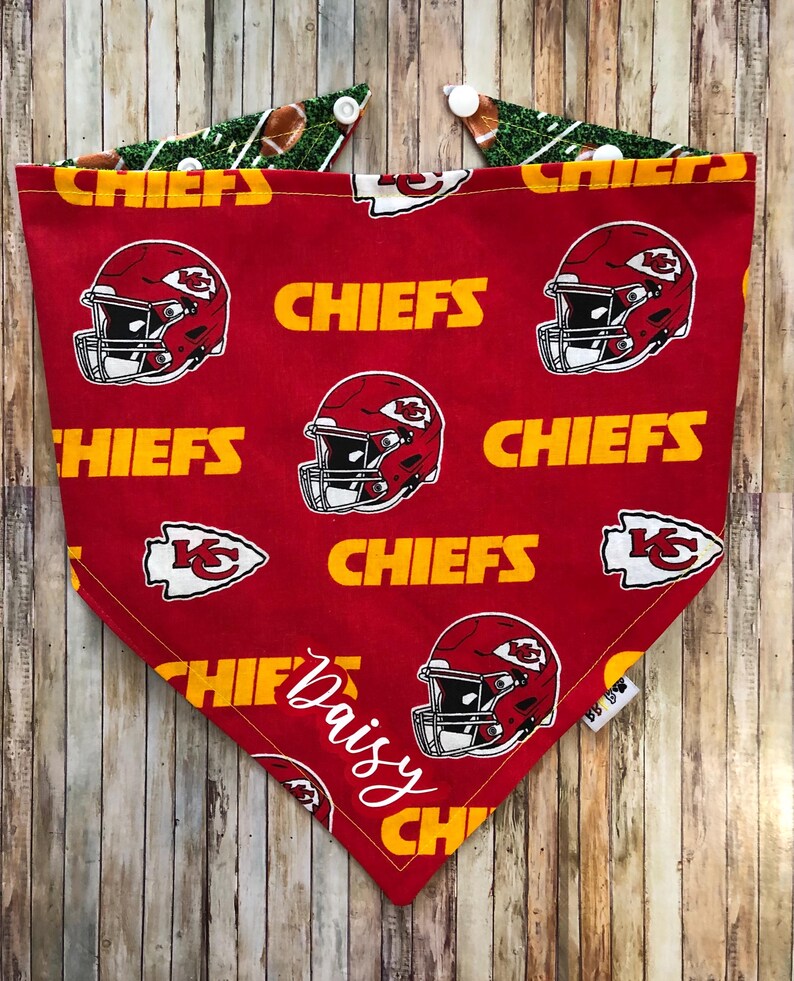 May include: Red and yellow bandana with a football helmet and "CHIEFS" repeated on the fabric. The bandana is personalized with the name "Daisy" in white cursive.