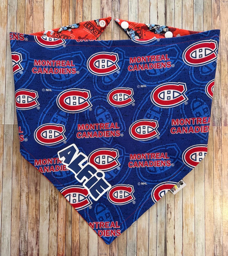 May include: A blue dog bandana featuring the Montreal Canadiens logo and team name. The bandana has a red and white design on the reverse side and includes the name "Alfie". The NHL logo is also visible.