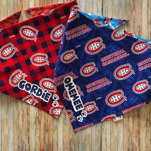 May include: Two dog bandanas featuring the Montreal Canadiens logo. One is red with a plaid pattern and the name "Gordie". The other is blue with the team logo and the name "Omemee". Both have snap closures.