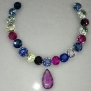 May include: A necklace made of various coloured gemstones, including blue, pink, and yellow. The necklace has a teardrop-shaped pendant.