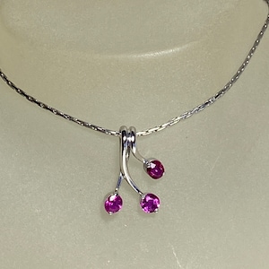 Peut inclure: Un collier en chaîne argent avec un pendentif composé de trois pierres précieuses roses serties d'argent.