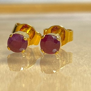 Puede incluir: Un par de pendientes de botón de oro con piedras redondas de rubí rojo oscuro.