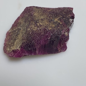 May include: A rough, purple and gold gemstone with a natural, irregular shape.