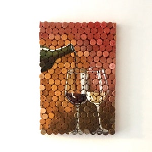 Puede incluir: Una obra de arte de pared hecha de corchos de vino, que representa una botella de vino vertiendo vino en dos vasos. Los corchos est&aacute;n dispuestos en una cuadr&iacute;cula, creando un efecto de mosaico. Los colores de los corchos van del marr&oacute;n claro al marr&oacute;n oscuro, con algunos tonos rojos y naranjas.