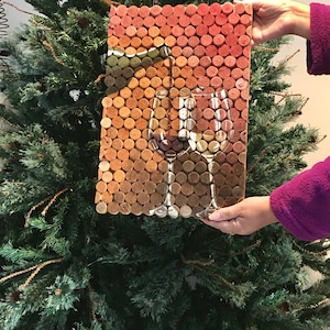 Puede incluir: Una pieza de arte de pared hecha de tapones de vino dispuestos en un patr&oacute;n de cuadr&iacute;cula. Los tapones son en tonos de marr&oacute;n, naranja y rojo. La imagen representa dos copas de vino con una botella de vino en el fondo.