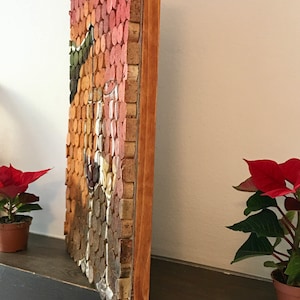 Puede incluir: Una obra de arte enmarcada hecha de corchos de vino, dispuestos en un patr&oacute;n de mosaico. La obra de arte presenta una variedad de colores, incluyendo rojo, naranja y marr&oacute;n. El marco est&aacute; hecho de madera y tiene un acabado natural.