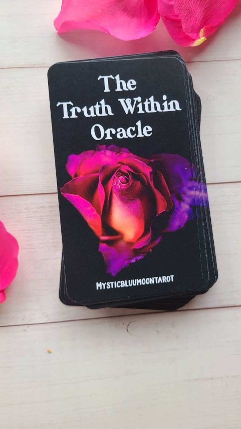 May include: A deck of oracle cards with a black background and a single pink and purple rose in the center. The text on the front of the deck reads "The Truth Within Oracle" and "MYSTICBLUUMOONTAROT".