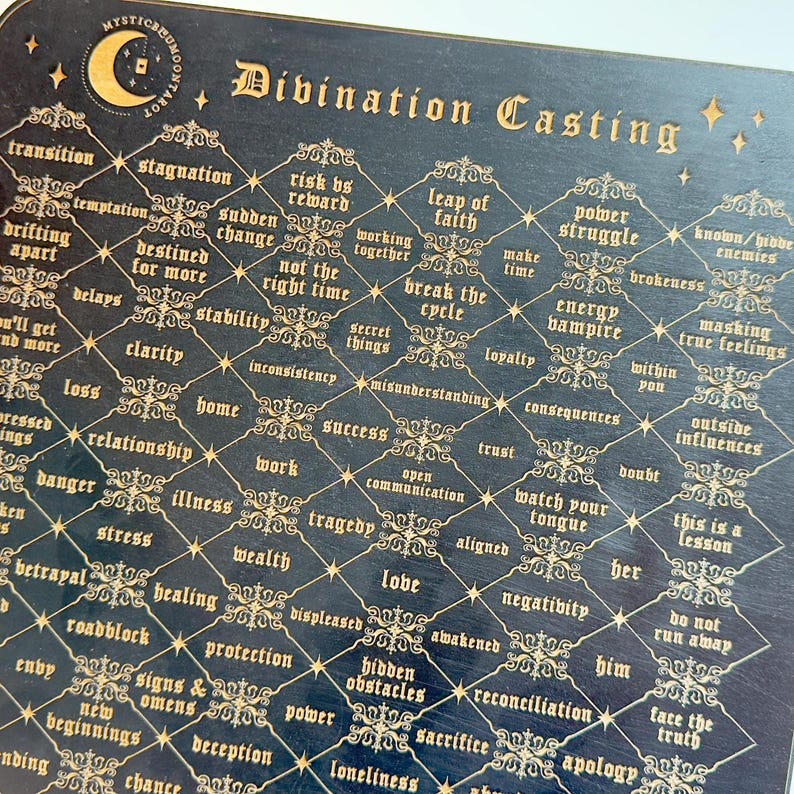 May include: A black divination board with gold lettering and a repeating diamond pattern. The board features words like "transition", "leap of faith", "power struggle", "energy vampire", "love", "hidden obstacles", "sacrifice", and "reconciliation".