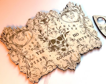 May include: A wooden Ouija board with a skull and floral design. The board features the alphabet, numbers 0-9, yes, no, and goodbye.